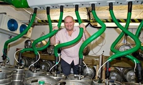 Man standing among green beer lines and stainless steel kegs